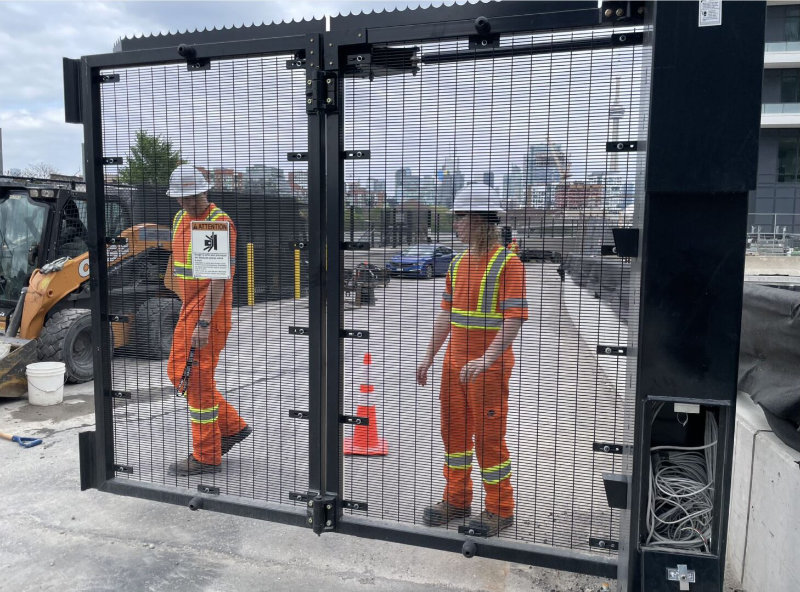 Two TTR workers standing behind a big black gate