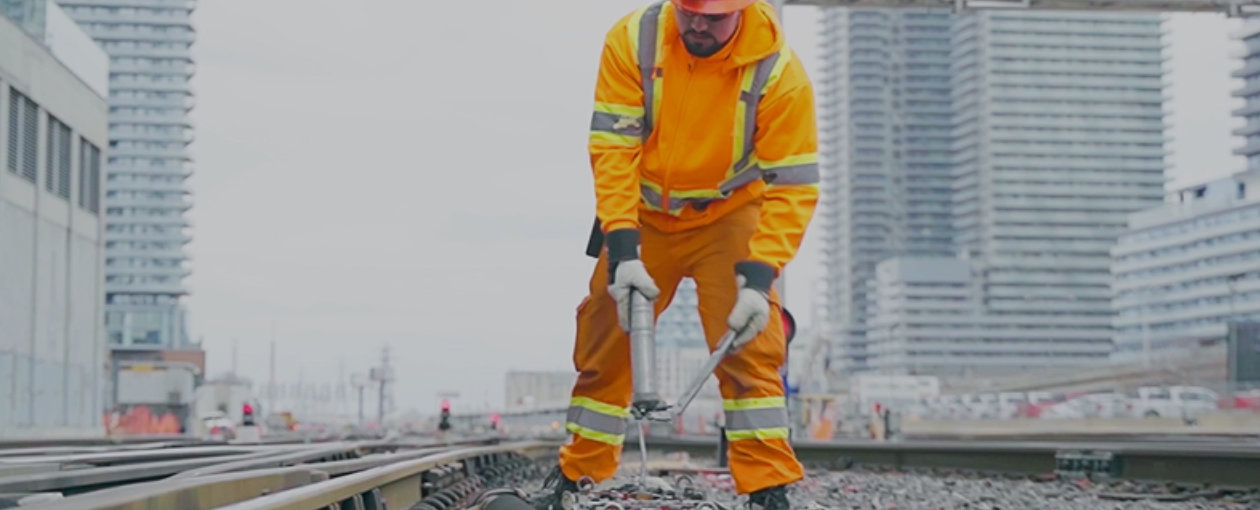 TTR Worker shown bent over with a tool on the tracks