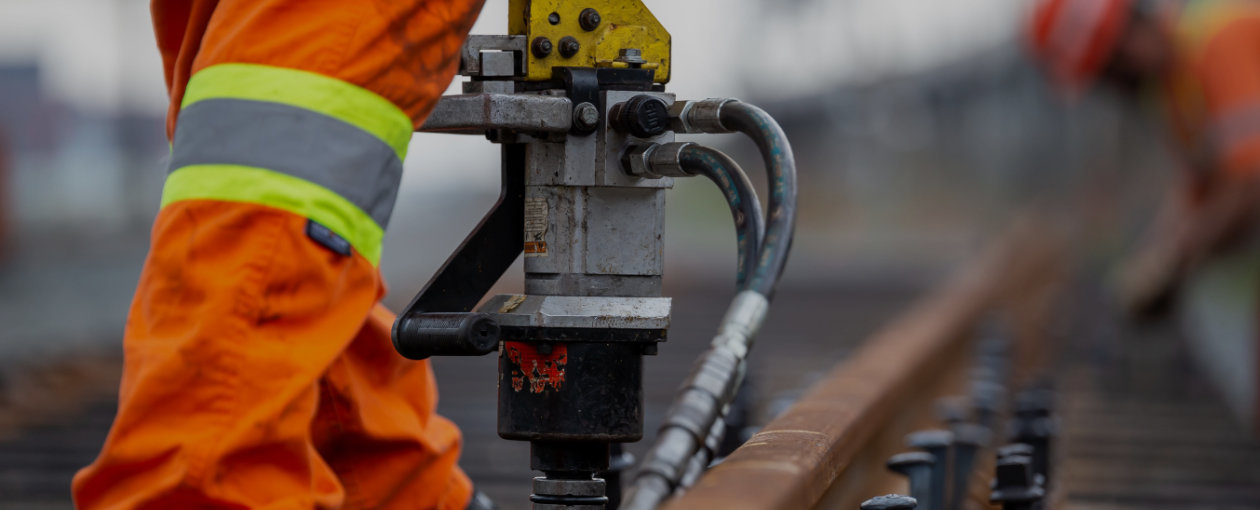 TTR Worker from knees down with a large tool working on track maintenance