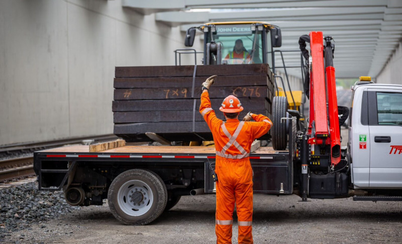 A TTR worker directing another worker who is using a large piece of machinery to put items on a truckbed