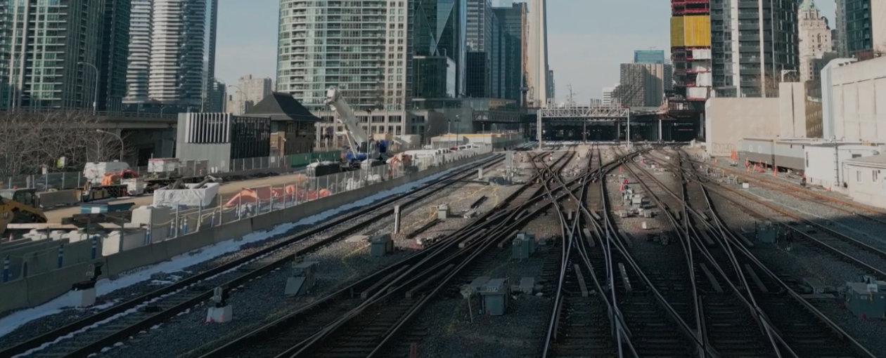 An image of train tacks and large skyscraper buildings